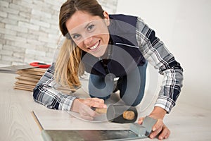 pretty happy female installing laminated floor with hammer