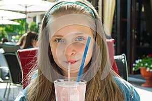 Pretty happy girl drinking strawberry smoothie