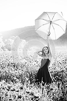 Pretty happy girl in field of poppy seed with umbrella