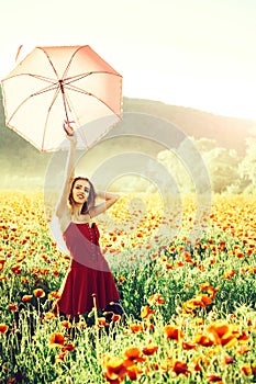 Pretty happy girl in field of poppy seed with umbrella