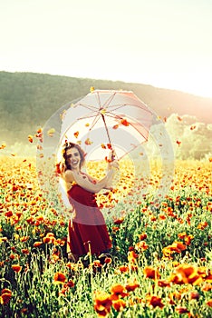 Pretty happy girl in field of poppy seed with umbrella