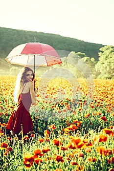 Pretty happy girl in field of poppy seed with umbrella