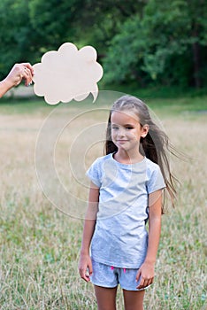 Pretty happy smiling thinking little girl posing summer nature outdoor with cloud of thoughts like in comic book. Kid`s portrai