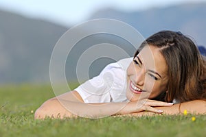 Pretty happy woman thinking on the grass and looking at side