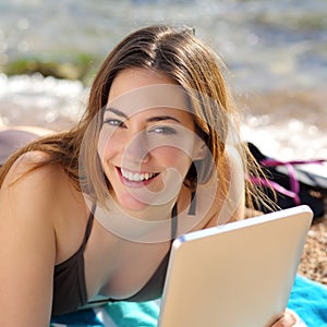 Pretty happy woman using a tablet on the beach