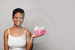 Pretty happy young woman with gift present box standing on white background