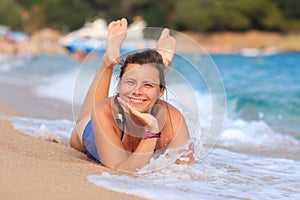Pretty happy young woman lies on sandy sea beach. Smiling girl on sea. Summer rest on beach. Sea vacation