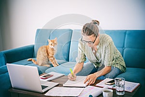 Pretty happy  young woman work home using laptop with her cat at sitting on the coach. Student freelancer lifestyle