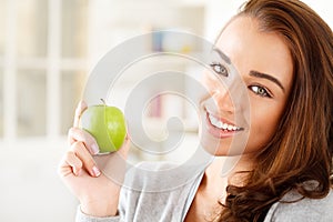 Pretty healthy young woman smiling holding a green apple