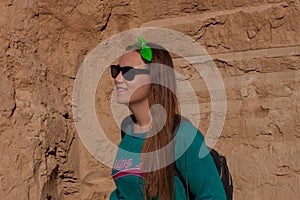 Pretty hiker girl with traveling backpack moving up on the mountain road. Smiling traveler woman looking away