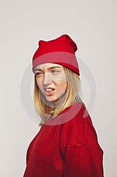 Pretty hipster girl growls like tiger wearing stylish red hat and sweatshirt
