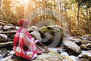 A pretty hipster girl with a plaid plaid on her shoulders in a hat and a yellow sweater and glasses with a mug of coffee