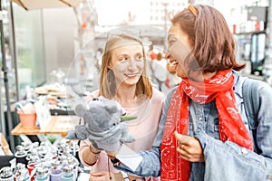 Pretty hipster girls friends having fun outdoor on the street. Shopping together for cute souvenirs and toys