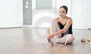 pretty hispanic ballerina smiling while preparing putting on dance ballet toe shoes and getting ready for class or rehearsal