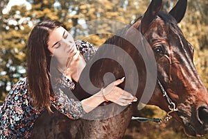 Pretty Hispanic brunette giving her horse a hug while riding him in the forest. love animals concept. love horses