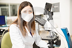 Pretty Hispanic chemist using a microscope