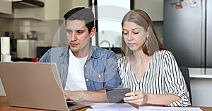 Pretty Hispanic couple using computer, pay bills, managing family budget