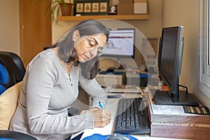 Pretty hispanic middle aged woman studying online course at home