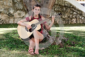 Pretty hispanic teenage girl playing an acoustic guitar