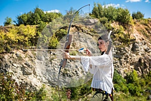 hunter girl shooting bow and arrow in the grassland