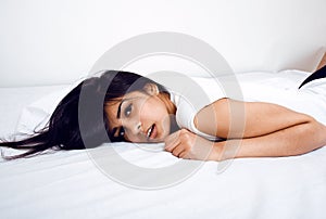 Pretty indian brunette real woman in bed smiling, white sheets, tann skin close up mulatto. cant sleep