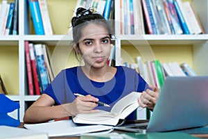 Pretty indian female student learning with books and computer
