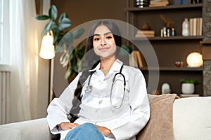 Pretty Indian woman doctor portrait posing on couch at home outside of working hours