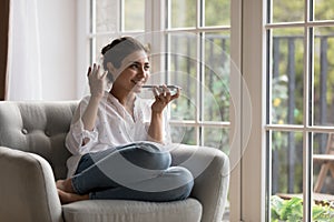 Pretty Indian woman holding smartphone talking on speaker phone