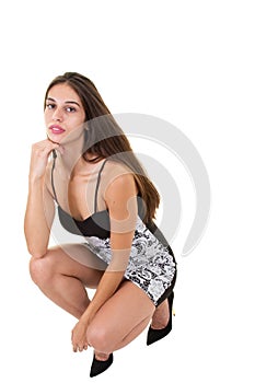 Pretty kneeling woman in fashion dress posing on white background