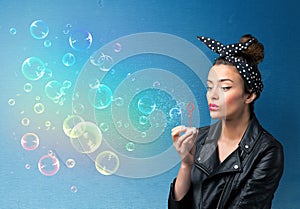 Pretty lady blowing colorful bubbles on blue background