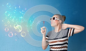 Pretty lady blowing colorful bubbles on blue background