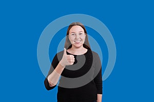 Pretty lady giving a thumbs up sweet smile on blue background