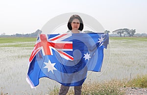 Pretty lady is holding Australia fabric flag in her hands nature view background