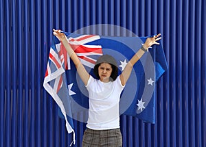 Pretty lady is holding Australia flag in her hands and raising to the end of the arm at the back