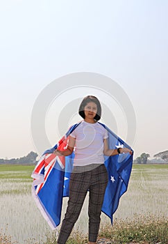 pretty lady in white shirt with Australia flag on her shoulder on nature view background