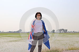 Pretty lady in white shirt with Australia flag on her shoulder on nature view background