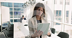 Pretty Latin businesswoman using tablet in modern boardroom