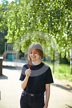 Pretty laughing young girl with closed eyes eating ice cream in the park, photography for blog or ad