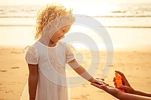 Pretty little baby girl in a white dress long blonde hair relaxing on the beach near sea, summer, vacation, travel