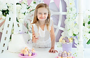 Pretty little blond girl standing in the beautiful decorated candy bar