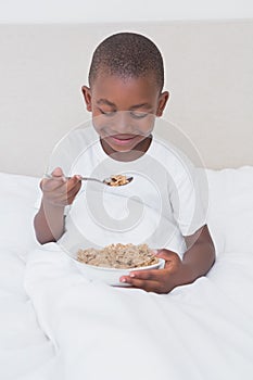 Pretty little boy eating cereals in bed