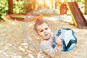 Pretty little boy playing with ball outdoor in the park