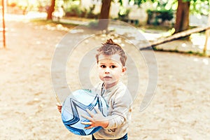 Pretty little boy playing with ball outdoor in the park