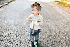 Pretty little boy riding scooter outdoor on the street