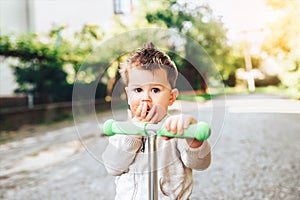 Pretty little boy riding scooter outdoor on the street