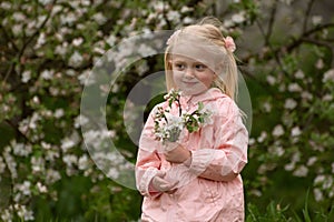 Pretty little caucasian girl with two tails enjoy spring apple blooming. Springtime. Preschool girl in flowering garden