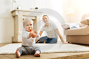 Pretty little child getting food from the bottle while the father sitting near