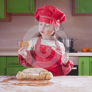 Pretty little child girl with chef hat holding cake and tasting it. Food, ÃÂooking process, sweets concept