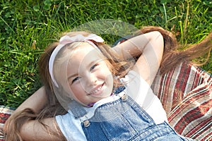 Pretty little child girl with closed eyes laying down on green grass in summer taking a nap