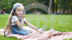 Pretty little child girl having conversation on her mobile phone in summer park